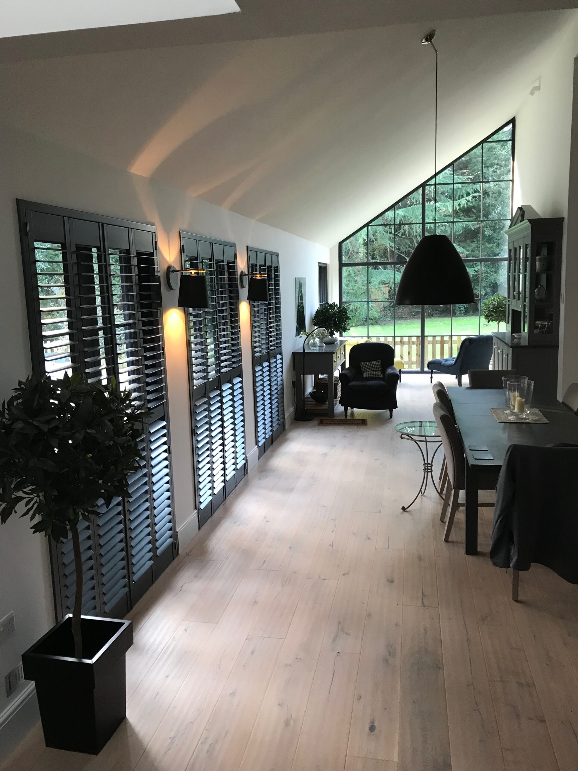 Modern style living room decor featuring grey plantation shutters with wide louvres.